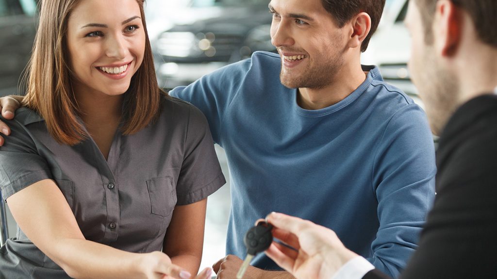 Young couple completed New Car Financing and the keys to the new SUV being handed to the wife