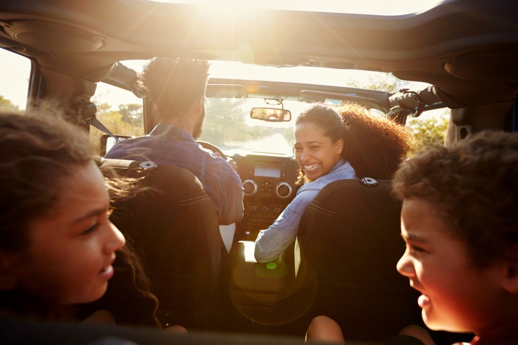 View from behind the back seat - family laughing on Summer Road Trip in SUV